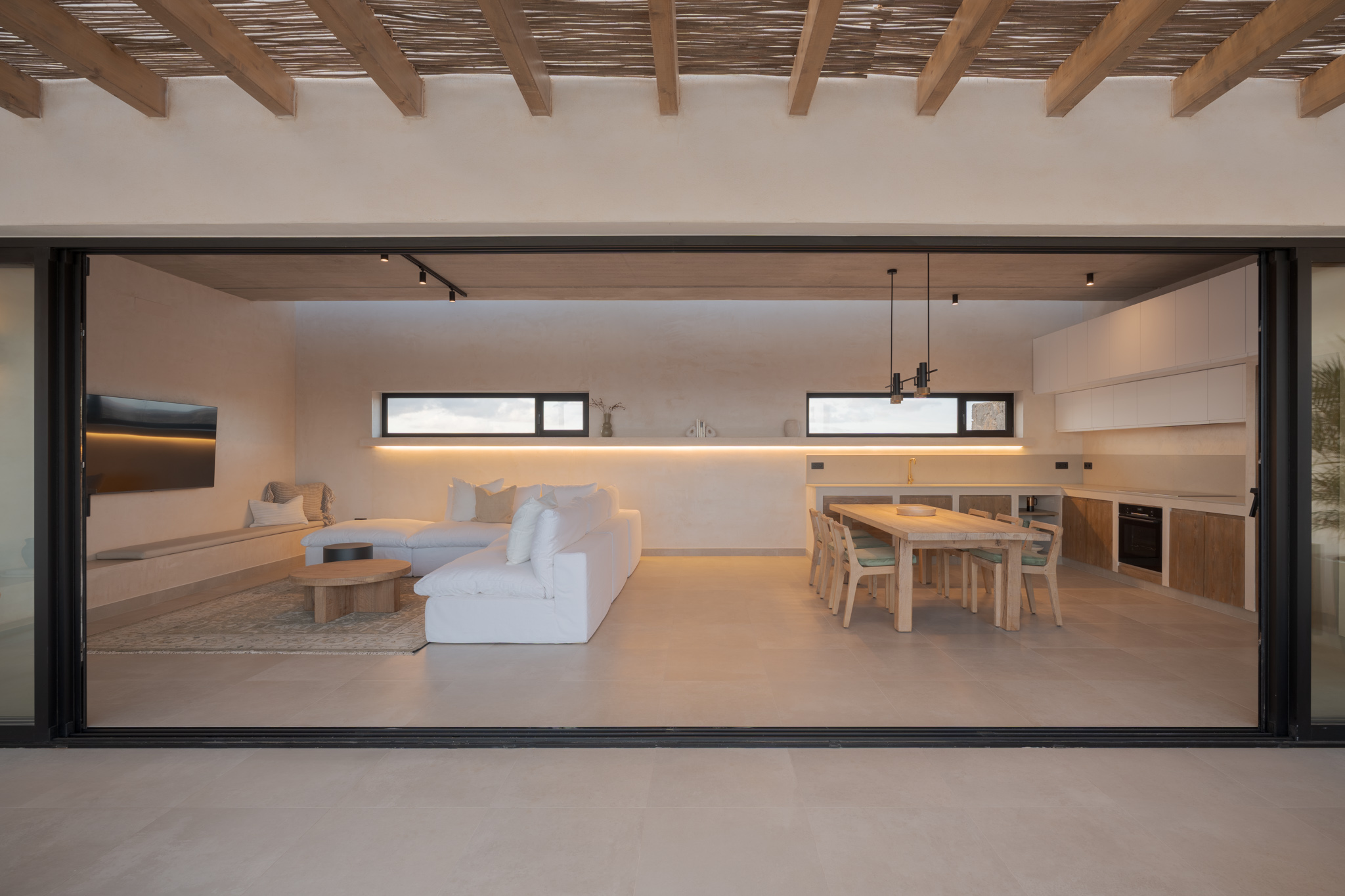 Living and dining area viewed through open sliding doors with wooden beam ceiling